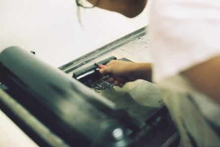 A girl preparing a metal plate for letterpress.