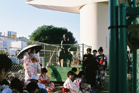 Japanese people wearing Yukata in summer around a statue of a girl.