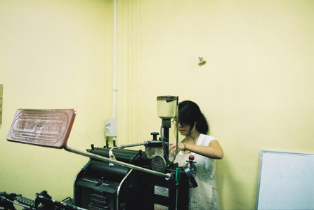 Michelle Yu doing maintenance work on a letterpress machine.