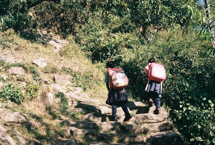Two Nepalese schoolgirls carrying schoolbags and walking up the mountain step in the Annapurna region in Nepal.