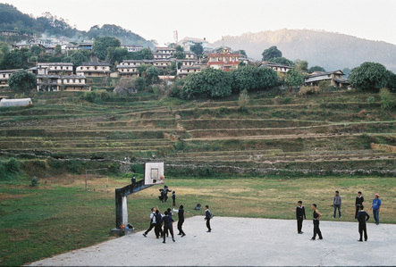 School children play basketball in front of terraced slopes and houses in the Annapurna region in Nepal.