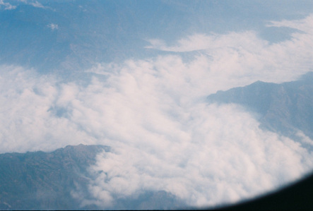 Photograph of clouds over a valley taken from a plane.