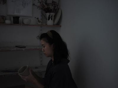 A girl working attentively on pottery on a gloomy day.