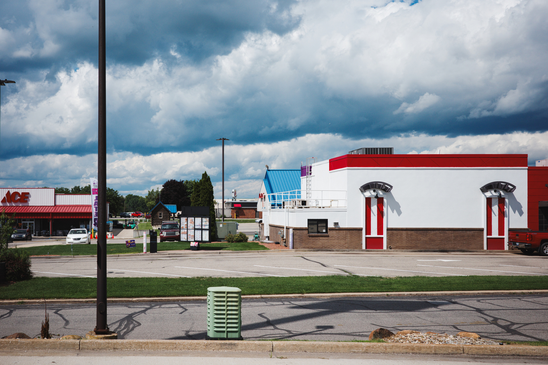Immerse yourself in the suburban atmosphere of Clare, Michigan, with this photo showcasing a fast food restaurant and adjacent retail spaces under a dramatic Midwestern sky. Captured on a Ricoh GR camera, this image highlights the clean lines of the archi
