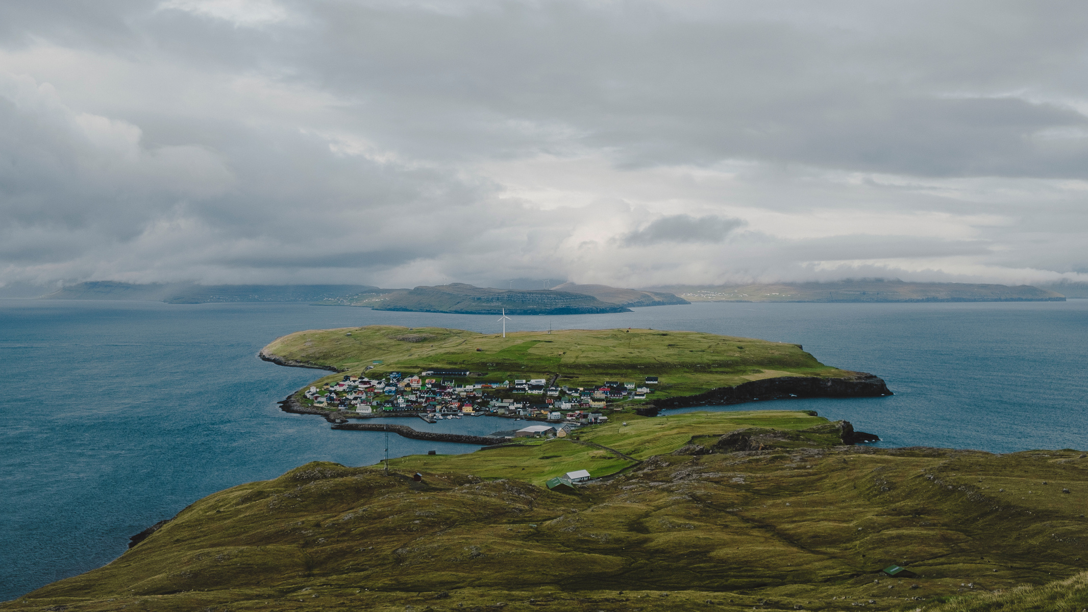 Discover the breathtaking beauty of Nólsoy Island in the Faroe Islands with this stunning landscape photo, captured on a Fuji XT-2 camera. This serene image showcases the quaint village surrounded by lush green fields and the vast Atlantic Ocean, offering