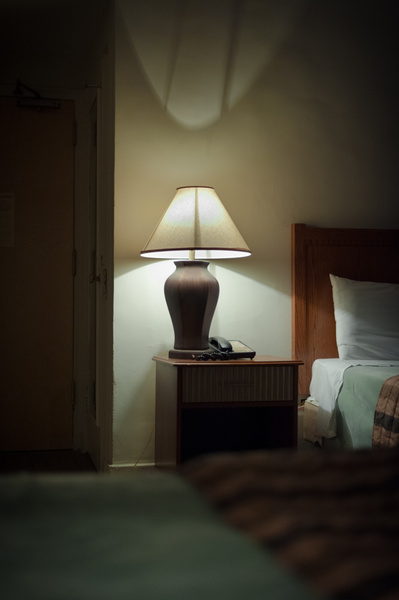 Moody shot of a lamp on a bedside table in a hotel room in New York City.