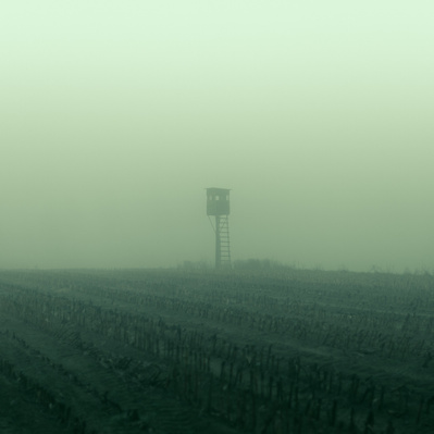 Cinematic photo of a distant shooting stand in the middle of an acre with greenish fog.