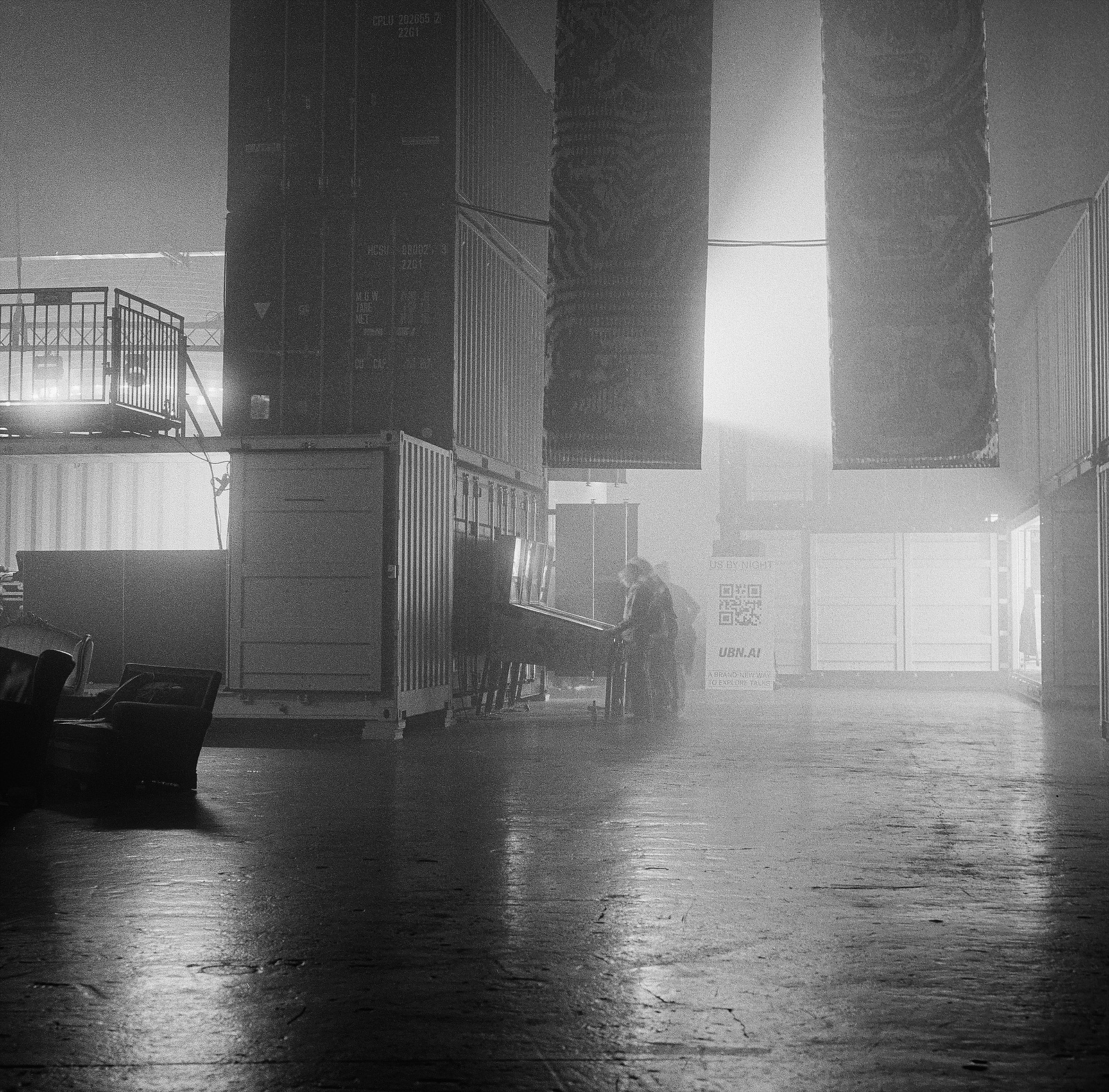 Black and white photo of a large hall with a distant pinball machine and haze. Shot on Hasselblad 500CM, Kodak Tri-X 400.