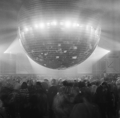Black and white photo of a gigantic disco ball hanging over a dancing crowd. Shot on Hasselblad 500CM, Ilford Delta 120.