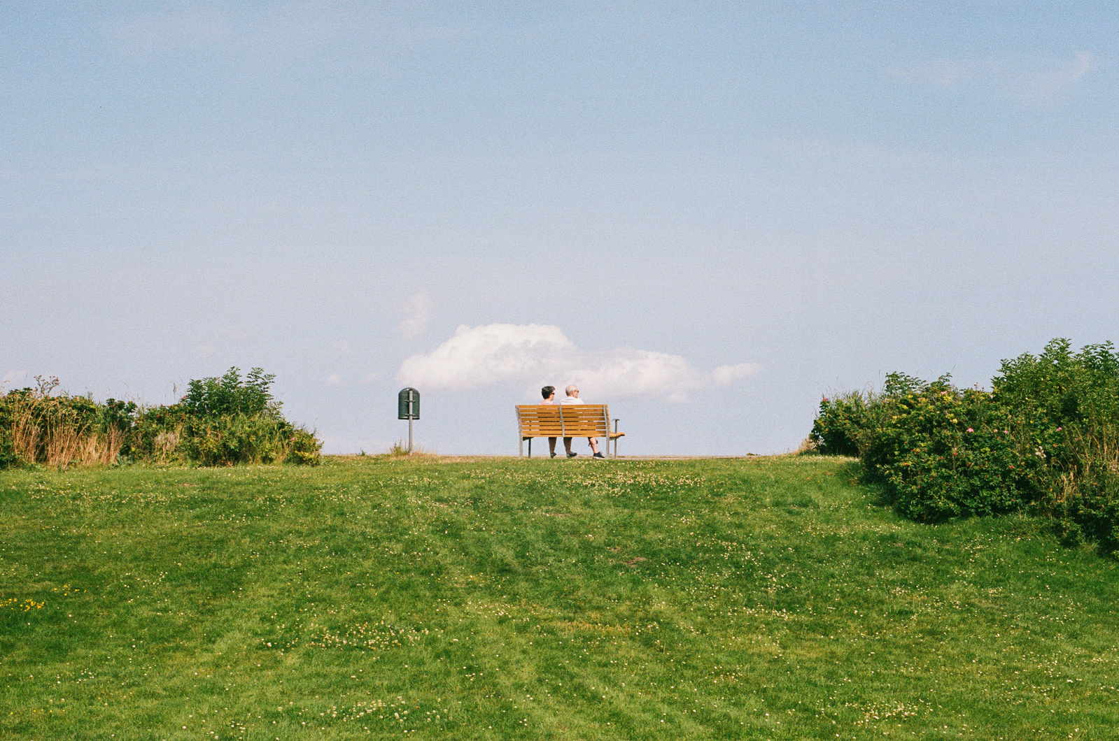 Analog photo of an old couple sitting on a bench with a view. Shot on Canon F1, Kodak Gold 200.