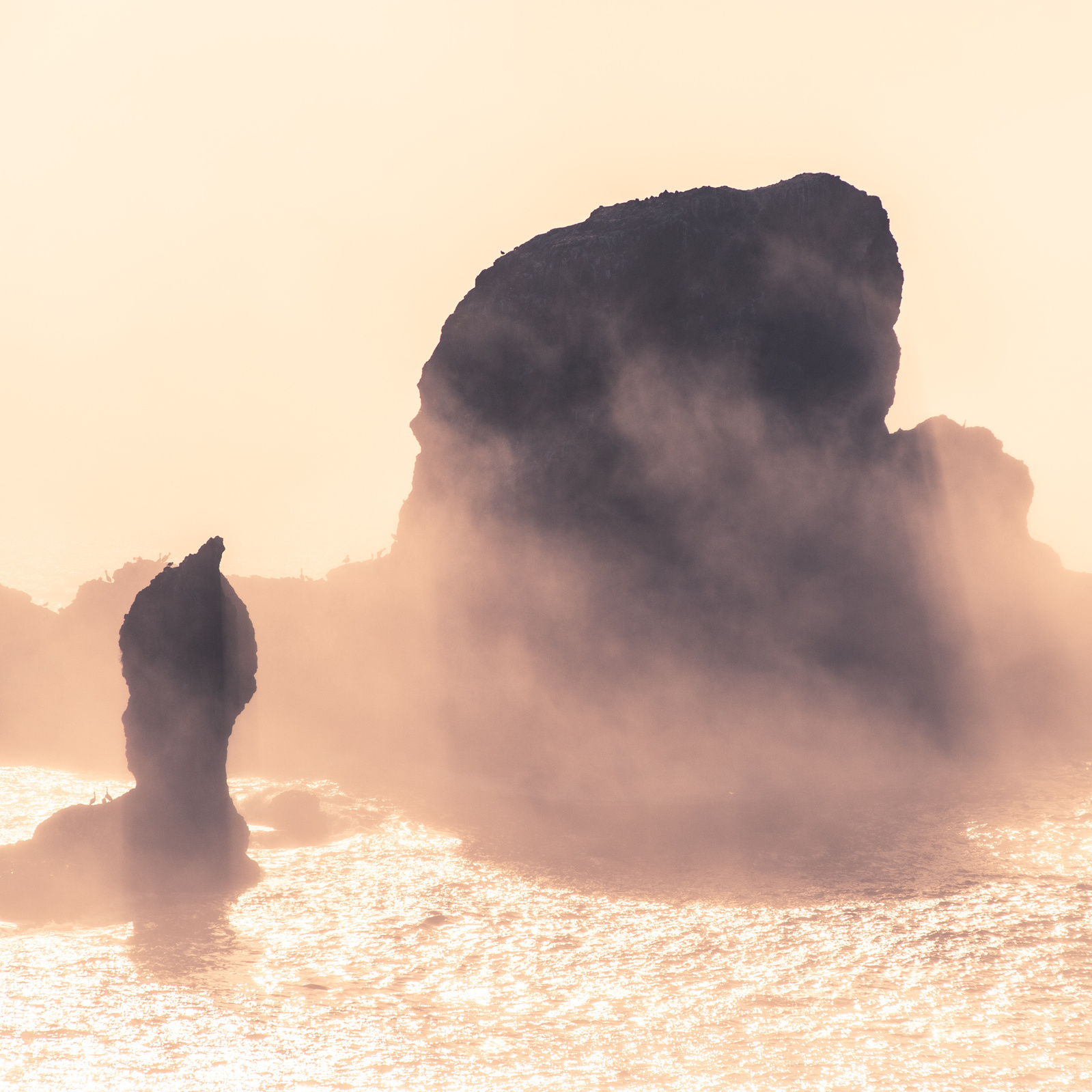 Hazy rock formation in the ocean.