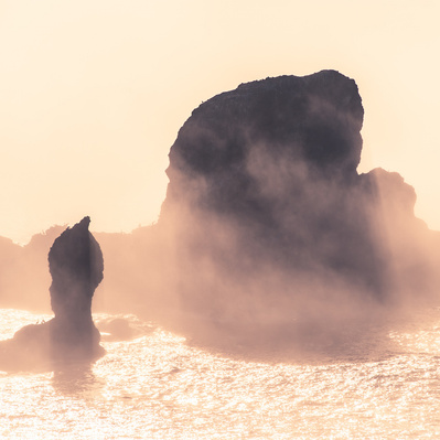Hazy rock formation in the ocean.