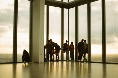 A group of people looking out the window of a skyscraper building in London. Shot on Canon F1, CineStill 800.