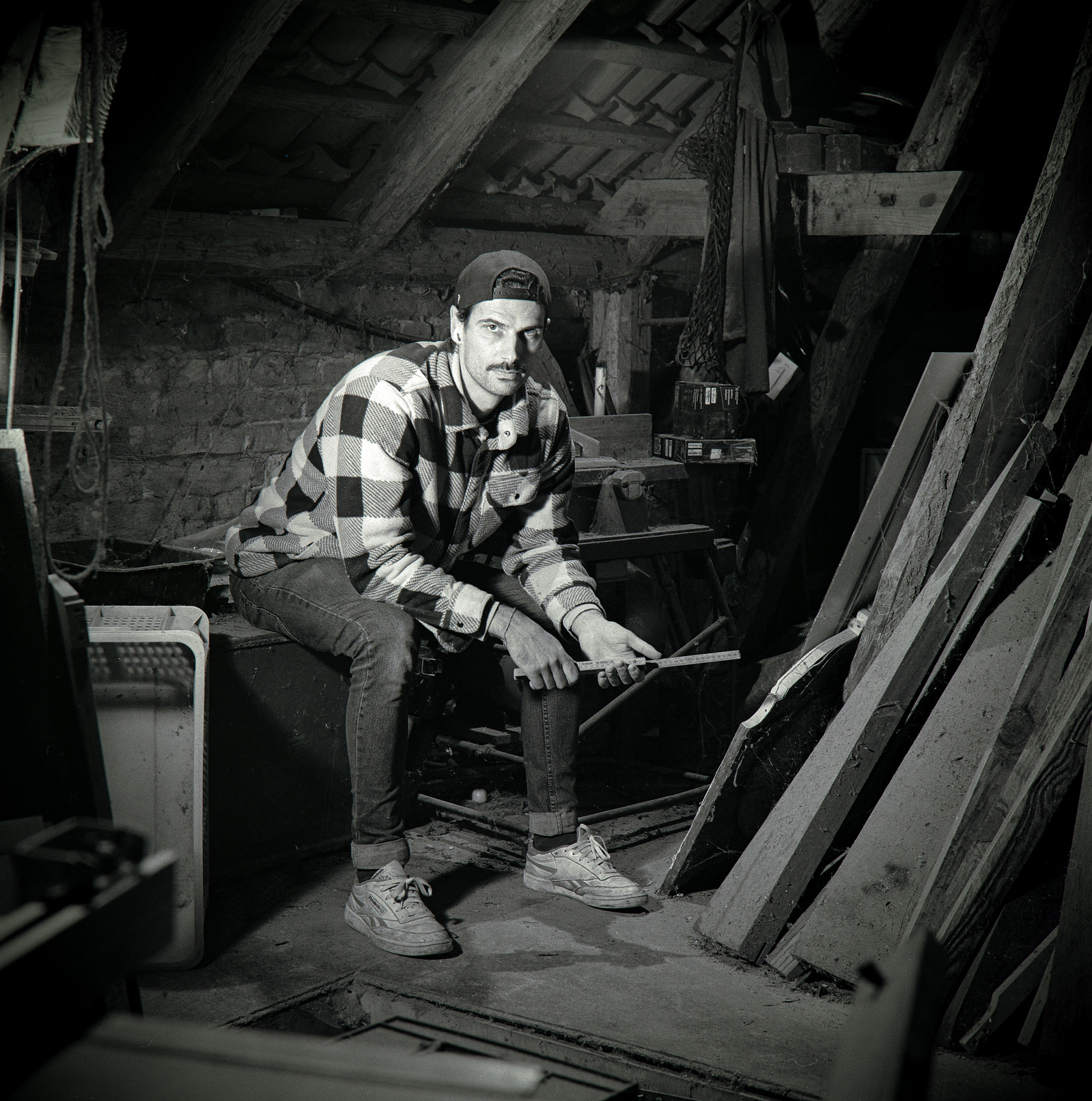 Black and white portrait of a youn handy man in an old workshop. Shot on Hasselblad 500CM, Ilford HP5.