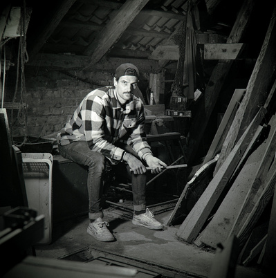 Black and white portrait of a youn handy man in an old workshop. Shot on Hasselblad 500CM, Ilford HP5.