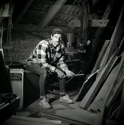 Black and white portrait of a youn handy man in an old workshop. Shot on Hasselblad 500CM, Ilford HP5.
