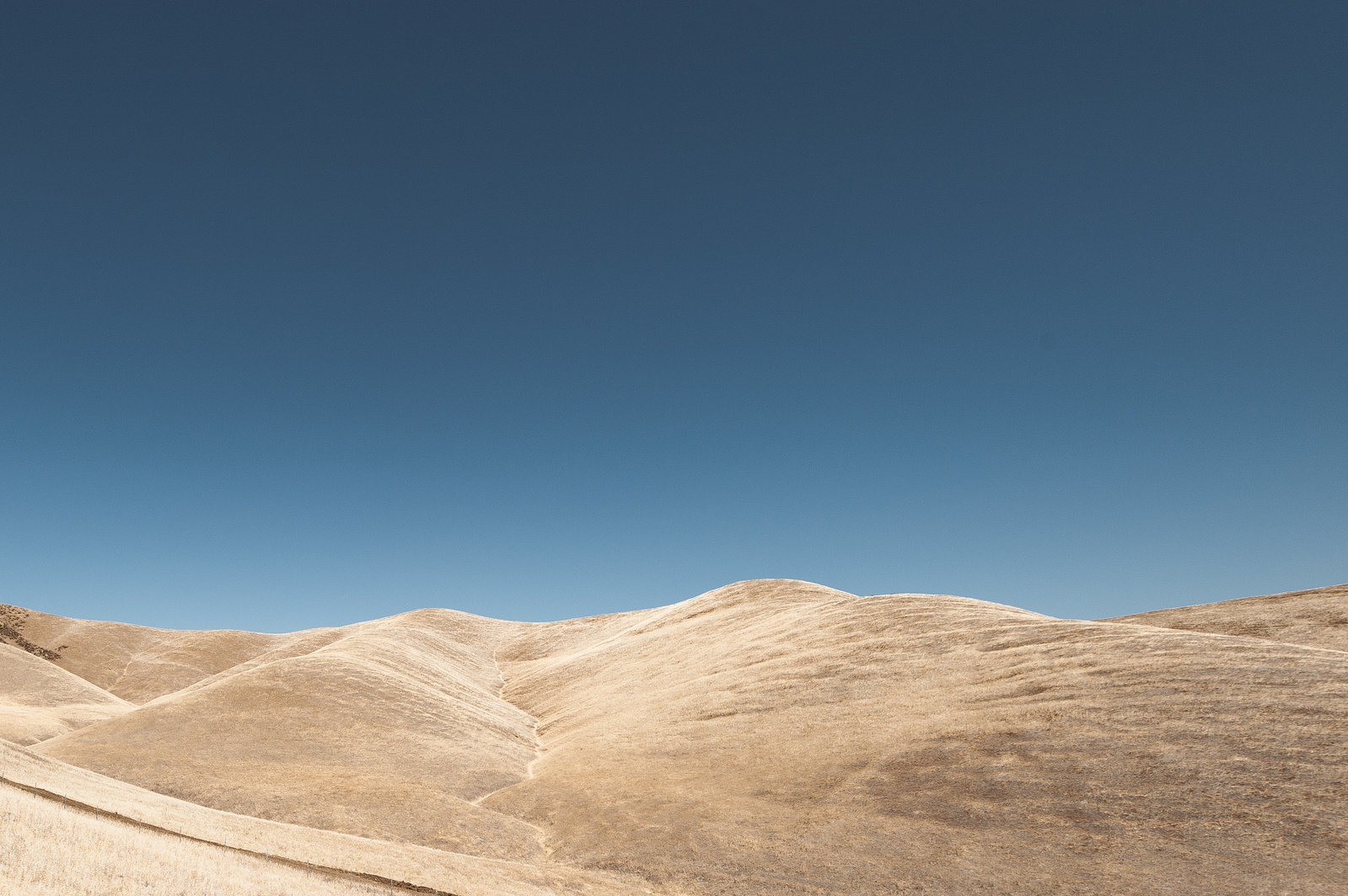 Abstract landscape photo with a clear sky and sandy warm hills in California.