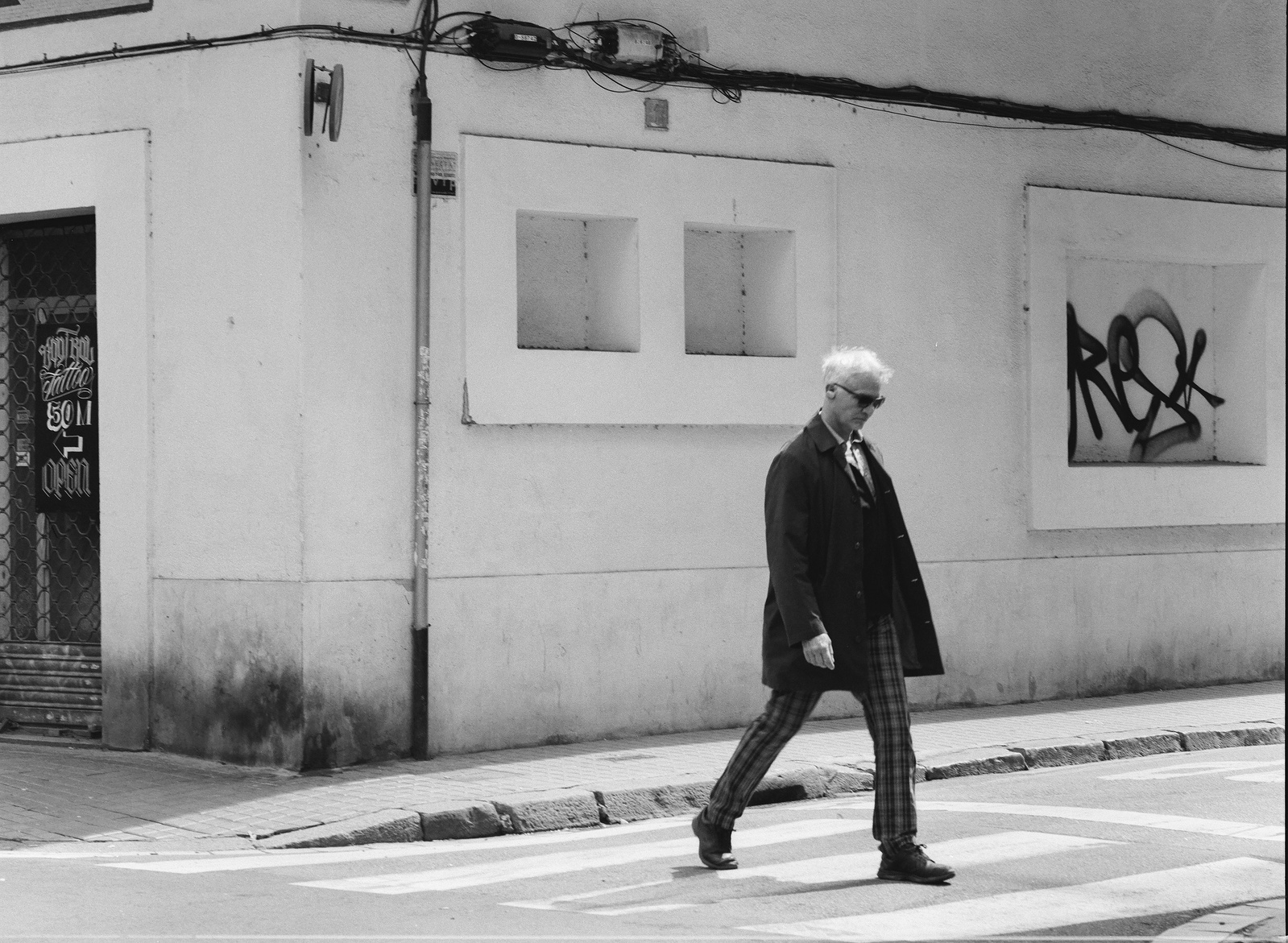 Black and white photo of an elegant man crossing the street in Barcelona, Spain. Shot on Hasselblad 500CM, Kodak Tri-X 400.