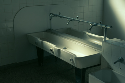 Abandoned bathroom with sinks and dramatic greenish light.