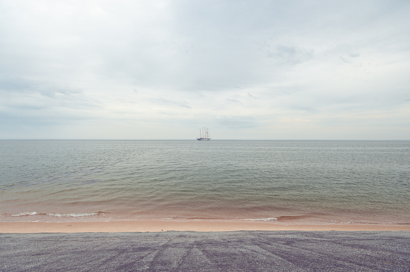 Distant ship by the coast with overcast sky.