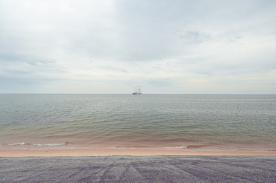 Distant ship by the coast with overcast sky.