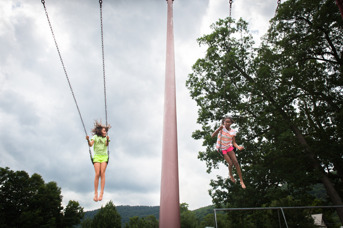 Allie Martin, 9, swings with Brianna George, 11, of Fort Greene, Brooklyn, on a playground at the Buckland Shelburne Elementary School Thursday, July 14. Brianna spent a week with the Martins, arriving Friday, July 8, as she has each summer for the past s