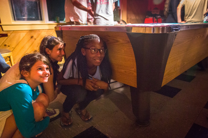 Allie Martin, 9, her sister, Katie Martin, 12, of Shelburne Falls, Massachusetts, and Brianna George, of Fort Greene, Brooklyn, hide behind a pool table from the Martins' mother, Jennifer, at the Ashfield Lake House, after watching the local band Kalliope