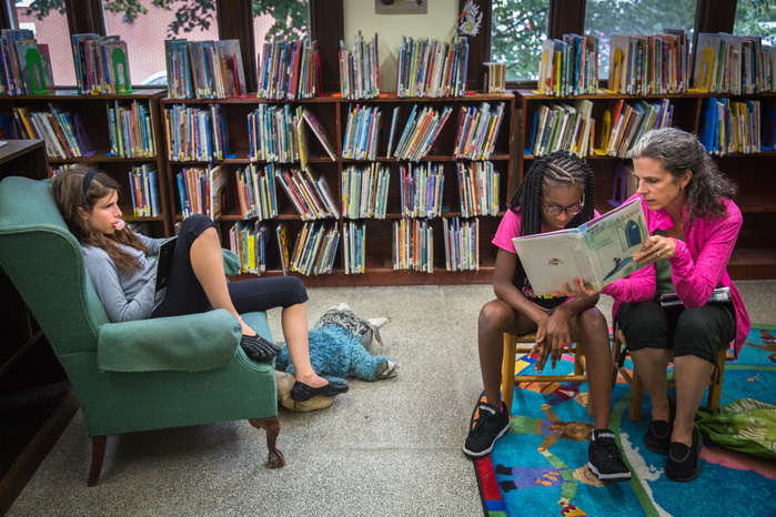 Katie Martin, 12, reads a book at the Arms Library in Shelburne Falls, as her mother Jennifer, helps Brianna George with reading a book Saturday, July 9. Brianna spent a week with the Martins, arriving Friday, July 8, as she has each summer for the past s