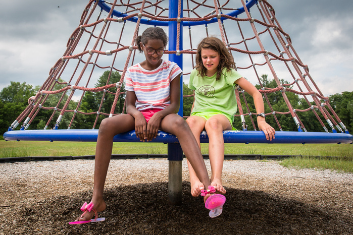 Brianna George, 11, of Fort Greene, Brooklyn, and Allie Martin, 9, sit together on some playground equipment at Buckland Shelburne Elementary School Thursday, July 14, their last day together. Brianna spent a week with the Martins, arriving Friday, July