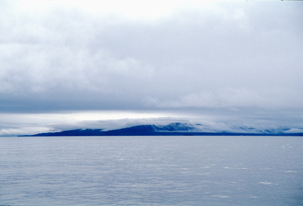 White and blue-toned arctic seascape with clouds and mountains