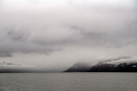 seascape with steep mountain cliffs on distance with dramatic sky