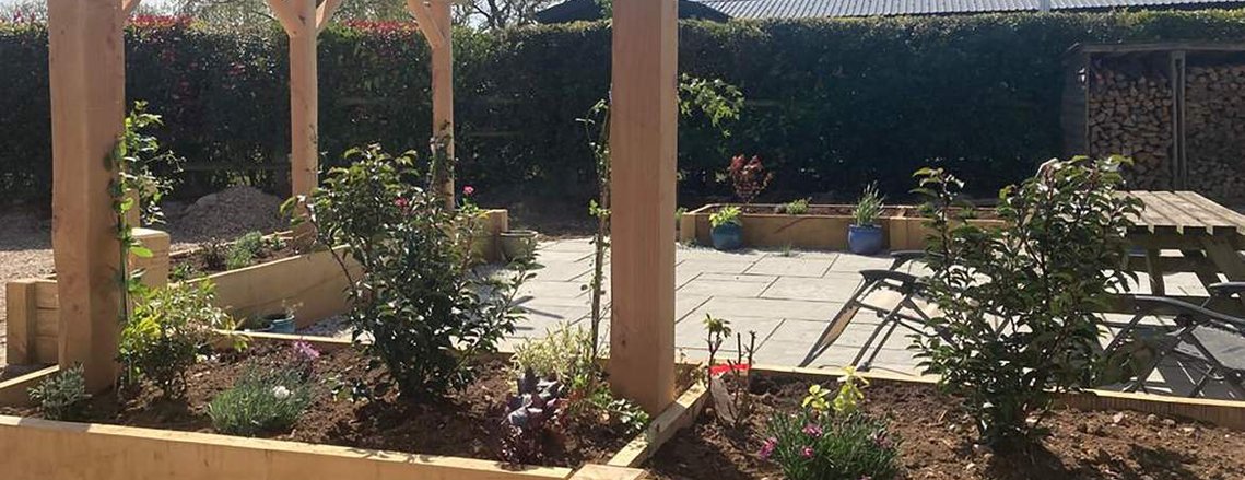 Oak timbers are used to build planters around paved area, garden landscaping in Devon by Seriously Good Landscapes