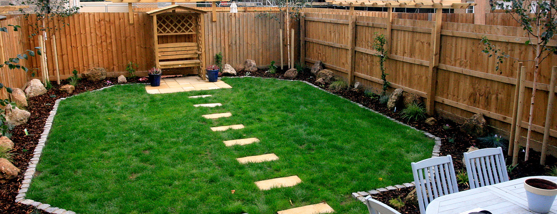 Garden landscaping as part of a new development in Devon. Seated area under a pergola with stepping stones leading up to it.