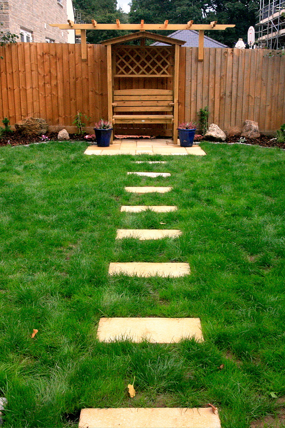 Garden landscaping as part of a new development in Devon. Seated area under a pergola with stepping stones leading up to it.