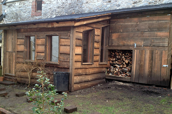 Man cave style garden room in Lustleigh Devon, Douglas fir waney edge board and natural roofing slates, including a log store