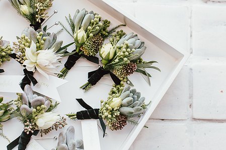 A tray of groomsmen&#x27;s personal flowers and boutonnieres for a black tie wedding at Boston&#x27;s Artist for Humanity.  