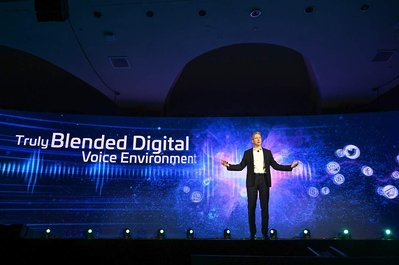 corporate company executive presenting at the company's annual summit with a large projection behind him