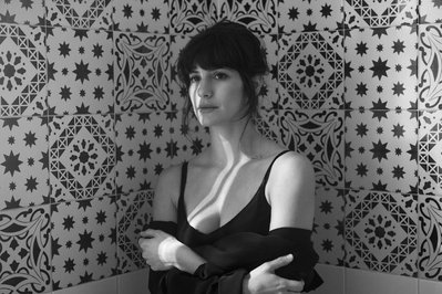 portrait of actress Sivan Mast in black and white on a patterned tile background