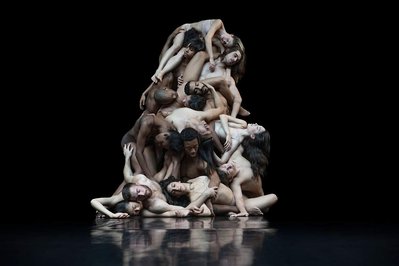 Dancers of Cedar Lake Contemporary Ballet laying on top of each other as a human sculpture on a black background