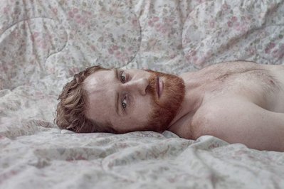 portrait of dancer Paul Zivkovich laying on a bed with flower sheets 