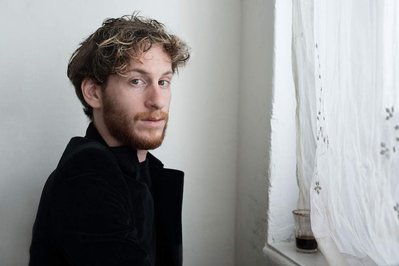 portrait of actor Elisha Banai near a window and a cup of coffee 