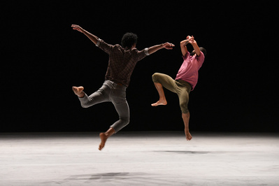 two dancers jumping on stage with their back to the camera