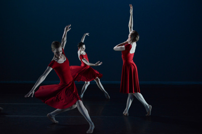 three female dancers with red dresses dancing on stage 