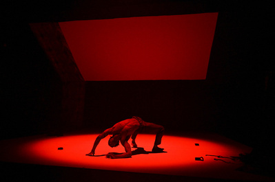 African American dancer under a red spotlight dancing on the stage's floor 