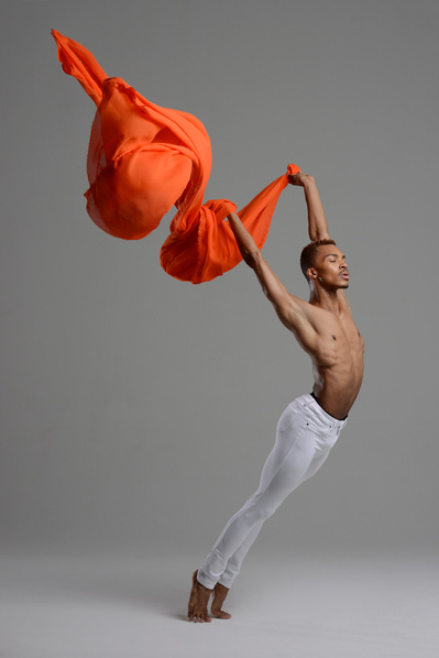 male dancer holding an orange fabric for  The Ailey School