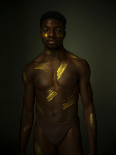 topless African American dancer with gold brush strokes on his body