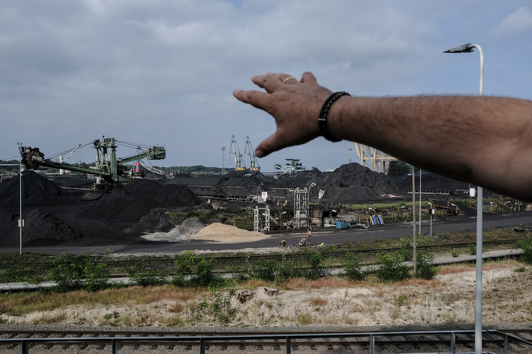 Tomasz Maślanka, resident of Świnoujście, showing the heaps of coal at the fuel teminal. The coal regularly catches fire and the accompanying fumes cause health hazards for local residents and safety hazards for fuel terminal infrastructure. Świnoujście,