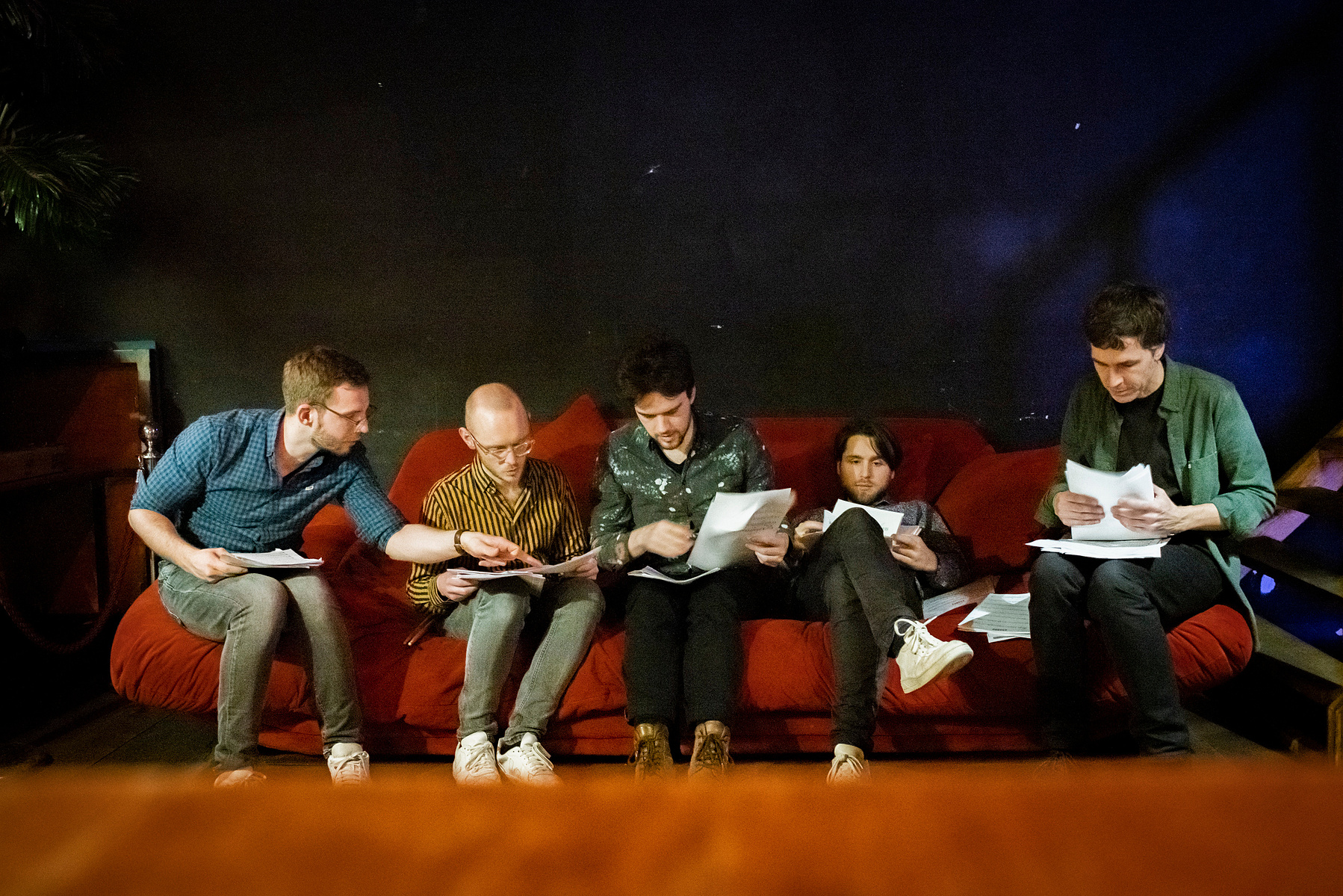 four jazz cats checking music sheets on a big sofa