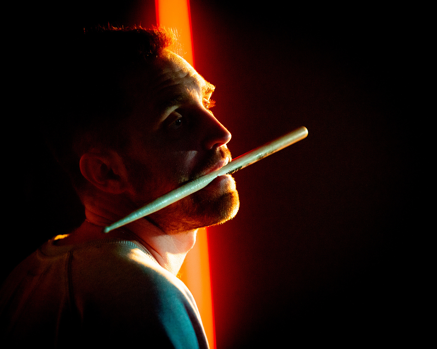 drummer close up with drum stick in mouth
