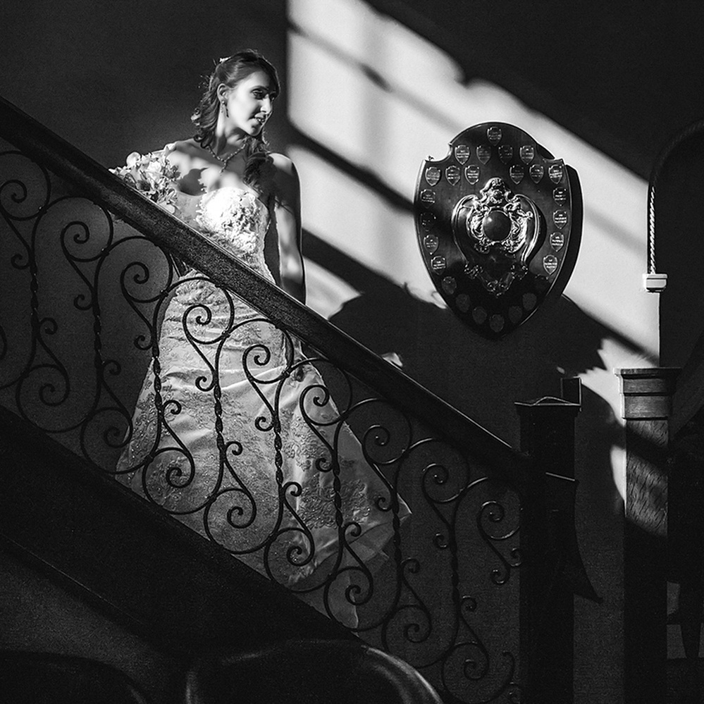 Bride in black and white on staircase at the Royal Ottawa Golf Club by Ottawa wedding photographer Frank Fenn